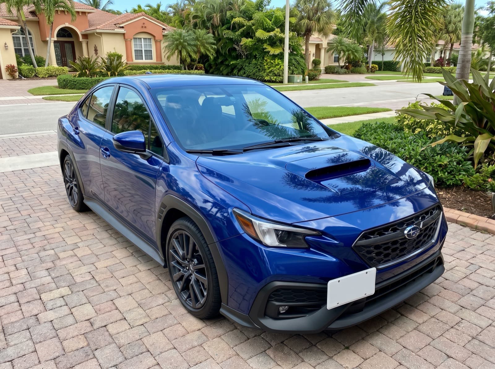 A blue sedan on a brick-paver driveway in Fort Lauderdale, FL, after a Bang AutoGlass mobile glass job